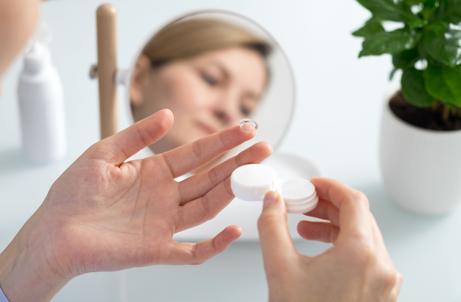 An individual holds a contact lens on their finger before inserting the lens.