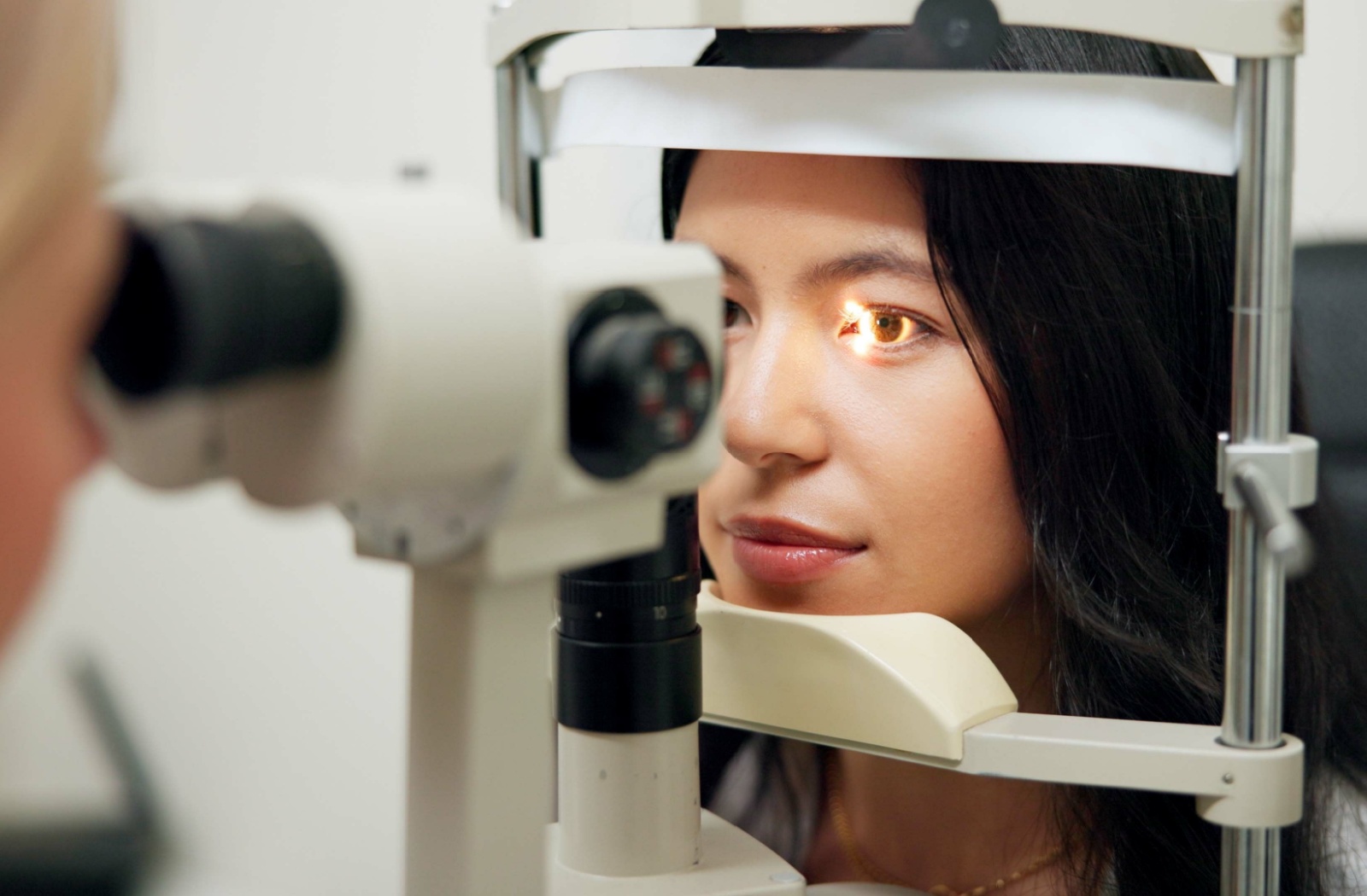 A close-up of a woman undergoing an eye exam with a slit lamp, highlighting precision and care in a professional eye care setting