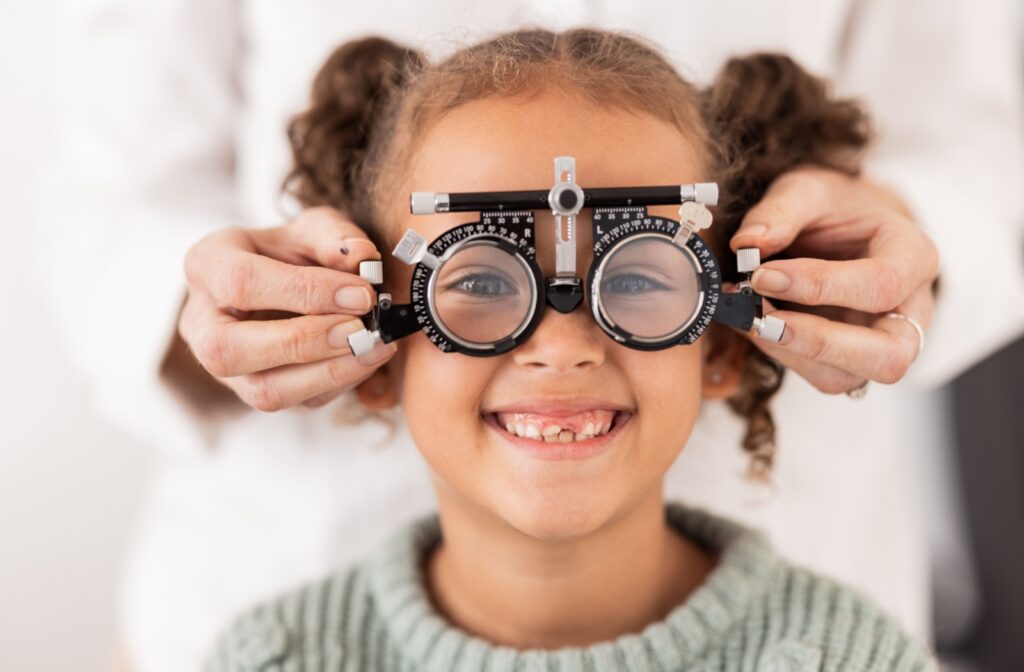 Child smiling at the camera during a vision test to monitor myopia progression.