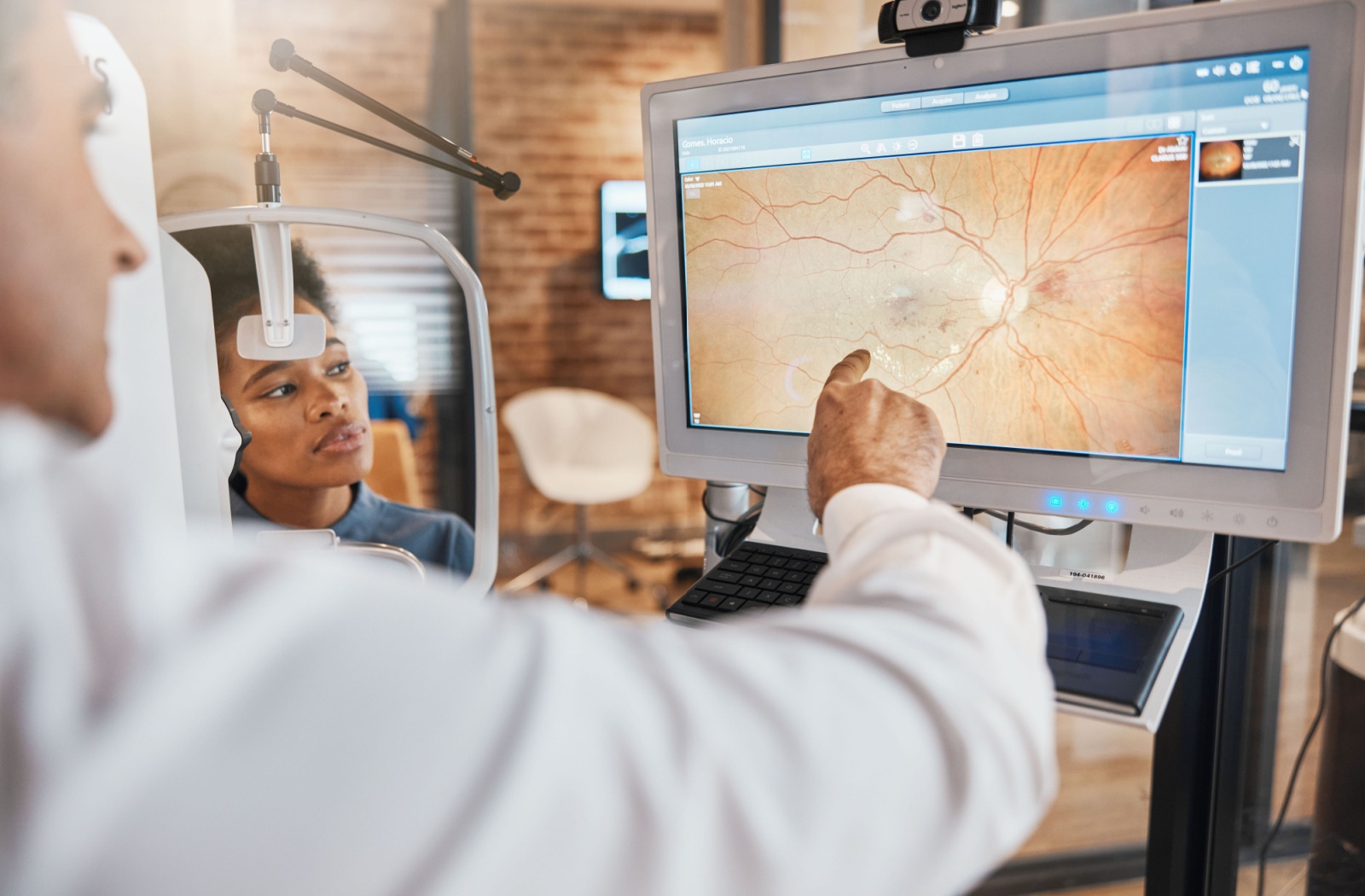 Optometrist examining a patient’s retinal image on a digital screen during an eye health evaluation.